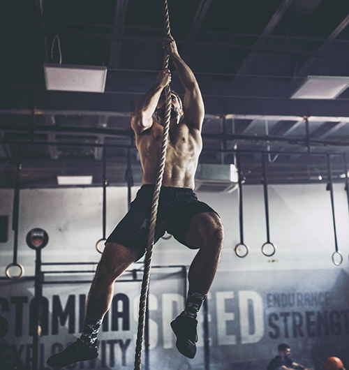 Muscular man climbing rope
